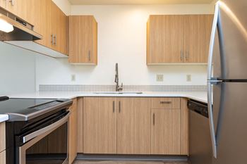 Kitchen with stainless steel refrigerator, black stove and wood cabinetry
